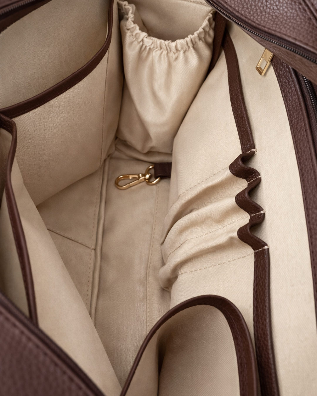 Close-up of a beige handbag with brown accents and a gold clasp.